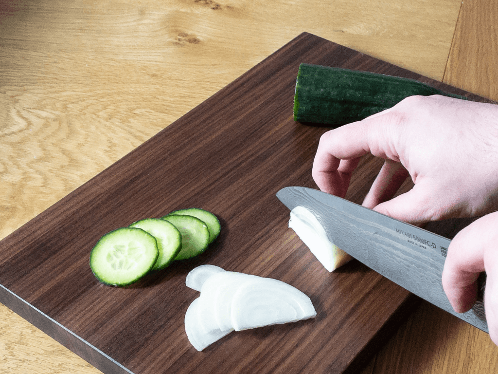 cutting vegetables with Japanese kitchen knife on walnut edge grain cutting board
