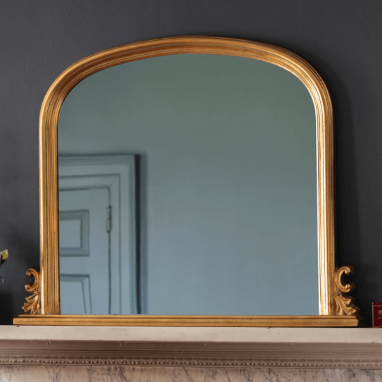 thornby gold arched mirror sitting on top of fireplace mantel