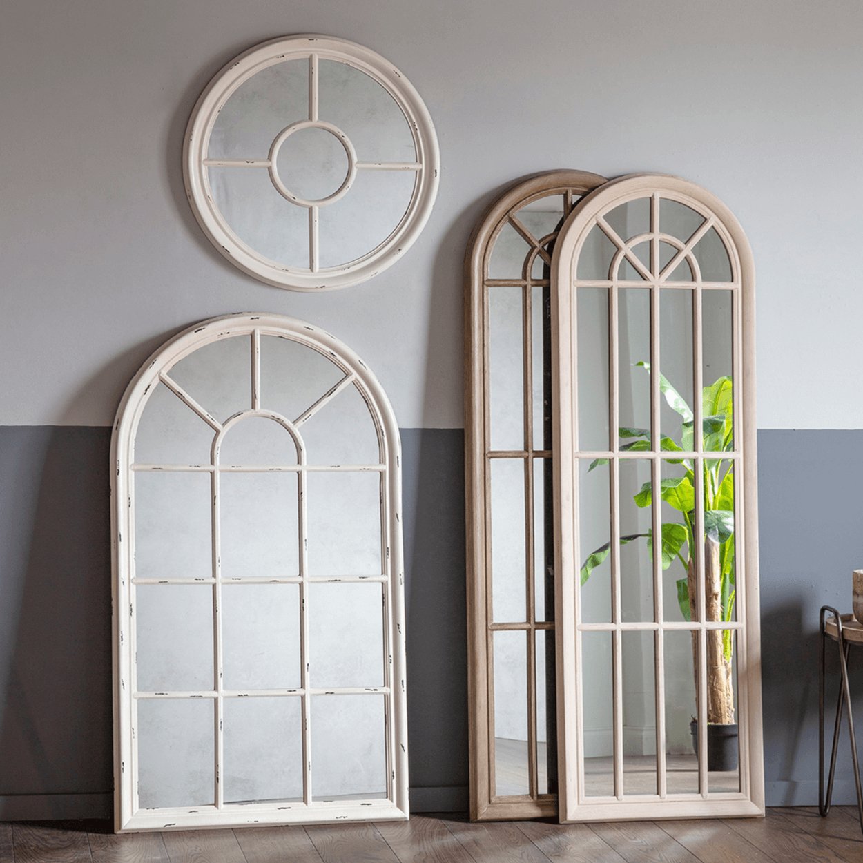white tall arched mirror besides round white mirrors